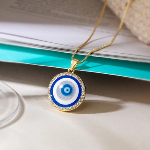 Gold plated evil eye pendant necklace with cubic zirconia on elegant blue book
