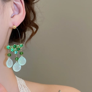Detail of vintage gold tassel earrings with green rhinestones and glass teardrop pendants