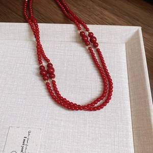 Detail view of double-layered red beaded necklace with golden metal spacers and glossy finish