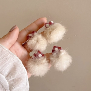 Handheld view of four cute beige plush ball earrings with red plaid heart and square patterns