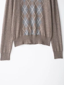 Detail of argyle pattern wool blend knit sweater with ribbed cuffs in brown earth tones