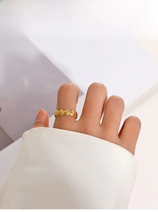 Detail of a gold shell-patterned stainless steel ring worn on a model's finger