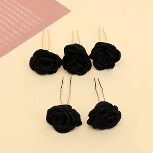 Detail of five black fabric rose hair pins with gold U-shaped metal clips for bridal hair