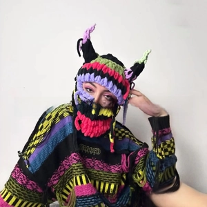 Detail of colorful chunky knit balaclava with devil horns and striped sweater texture