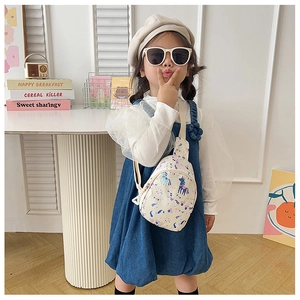 Girl wearing a cream cartoon unicorn crossbody bag with denim dress and beige beret