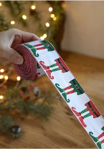 Detail of Christmas ribbon with festive elf leg print and glitter on fabric material