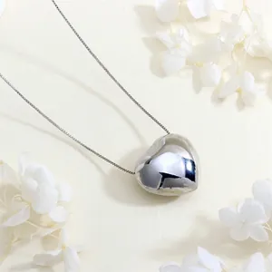 Detailed view of a silver 3D heart pendant on a box chain with floral background