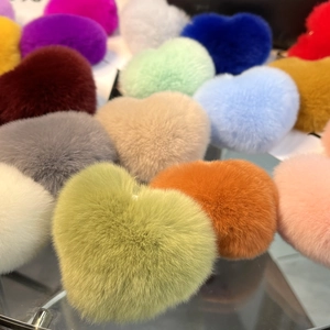 Close-up of heart-shaped rabbit fur keychains in various vibrant colors on glass