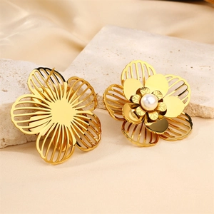 Golden hollow flower earrings with white pearl center on a premium textured stone base