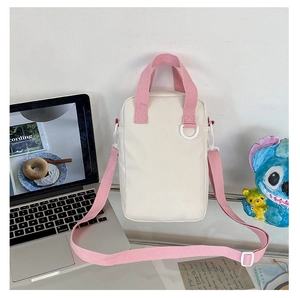 Detail of a beige canvas bag with pink handles and strap in a clean lifestyle setting