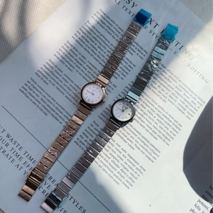 Detail of silver and rose gold metal strap watches with round dial on a magazine background