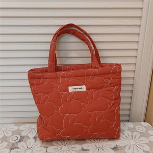 Detail of orange quilted tote bag with rabbit patterns and Simple Wish woven label