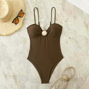 Detail of chocolate brown swimsuit with golden shell accent and thin straps on stone tile