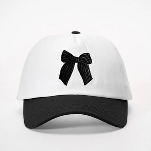 Dettaglio del ricamo a fiocco su cappello da baseball bicolore in cotone con visiera nera