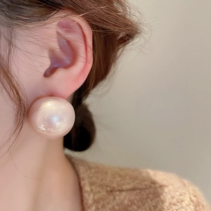 Primo piano di una modella che indossa grandi orecchini a perno tondi in perla rosa