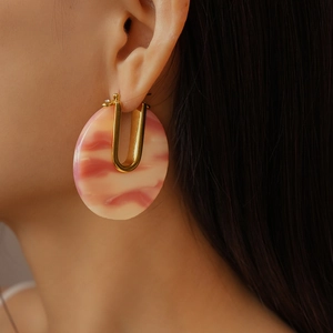 Detail of 18k gold plated U-shaped earring with pink marble pattern acetate on ear