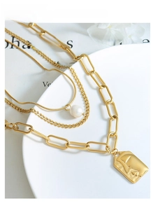 Detail of triple-layer gold necklace featuring portrait pendant and natural freshwater pearl