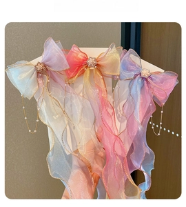 Detail of gradient mesh bow hair clip with pearl clusters and delicate gold tassels