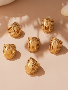 Detailed view of six gold-plated chunky rings featuring intricate hollow filigree patterns
