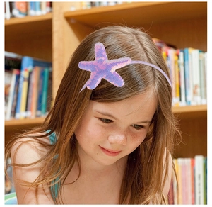 Close-up of a child wearing a purple headband with a large sequin starfish decoration