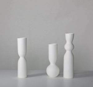Detail shot of three white matte ceramic vases featuring unique horizontal hand-crafted textures