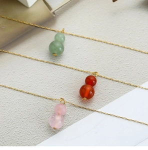Detailed macro view of gourd-shaped pendants in green, red, and pink on gold chains