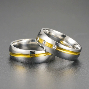 Vue macro détaillée de bagues de couple en acier inoxydable bicolore avec cristal.
