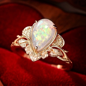 Vintage leaf textured ring with water drop opal stone on luxury red velvet background