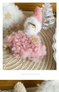 Detailed close-up of a pink plush angel ornament with knitted hat and gold heart detail