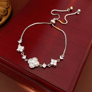 Close-up of silver clover bracelet with white zircons on a dark red jewelry box