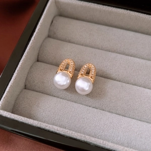 Macro shot of 18K gold plated arch earrings with pavé crystals and white pearls