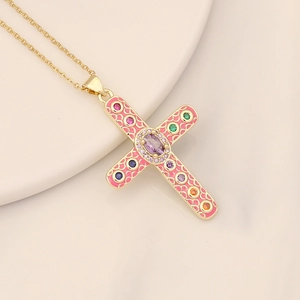 Gold cross necklace with pink enamel and multicolor zircons on a ceramic tray