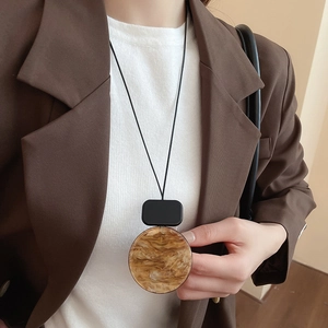 Close-up of geometric resin pendant necklace with brown marble texture and black leather cord