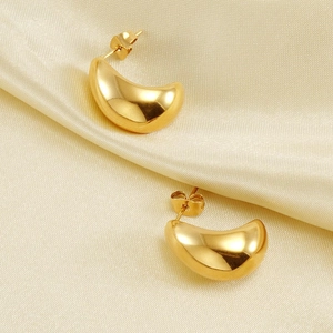Pair of elegant 18K gold plated C-shaped titanium earrings on soft silk fabric