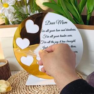 Close-up of removing protective film from gold acrylic heart frame on Mother's Day gift