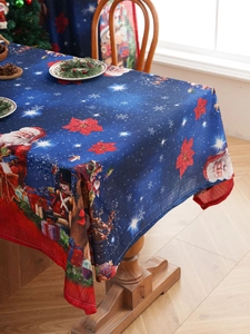 Detail of Christmas tablecloth featuring Santa and Nutcracker on a festive wood table