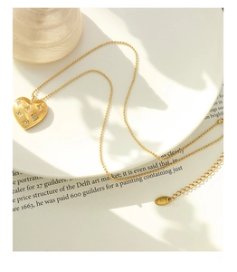 Close-up of heart-shaped 18K gold pendant with star-engraved diamonds on a beaded chain