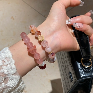 Detail of strawberry quartz and agate beaded bracelets worn on wrist with luxury bag