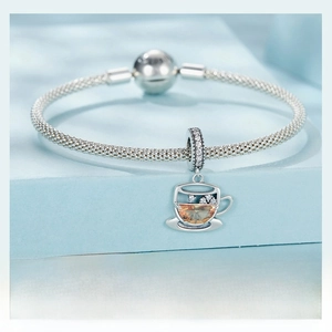 Detailed view of S925 silver coffee cup charm with orange gemstone on a woven bracelet