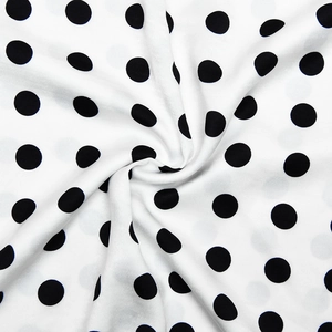 Gros plan détaillé montrant la texture douce et les drapés du tissu en satin à pois noir et blanc