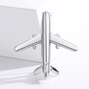 Polished silver airplane brooch pin for shirts displayed on a white minimalist pedestal