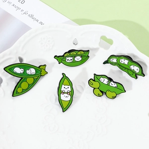 Detailed close-up of five cute enamel cat pea pod pins on a decorative white display plate