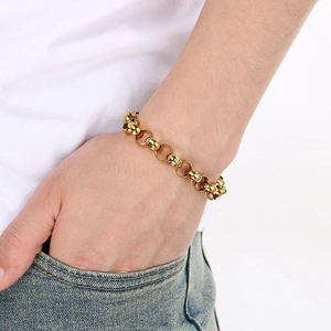 Detailed view of a thick golden link chain bracelet worn by a model on denim