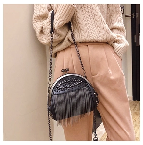Detail of black crossbody shell bag with metallic rivets and long tassel chains