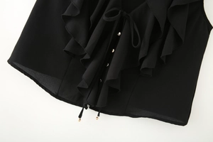 Détail du haut sans manches à volants noirs avec boutons dorés et perles de cordon