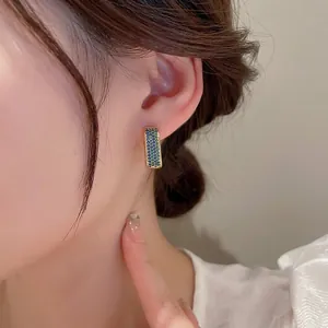Luxe geometric zircon huggie earrings in gold with blue-green gradient stones