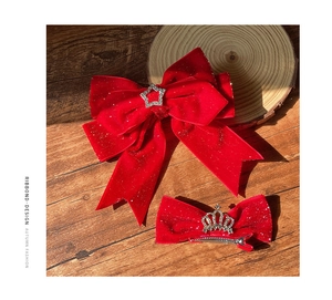 Detail of red velvet bow hair clips with rhinestone crown and star on a wooden background