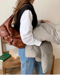 Detail of soft brown leather hobo bag carried by a model in a stylish indoor setting