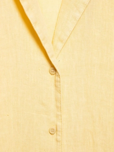 Detailed macro view of the cream linen shirt neckline and natural fabric texture