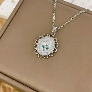 Elegant silver rose flower pendant necklace with green leaf accents on jewelry box